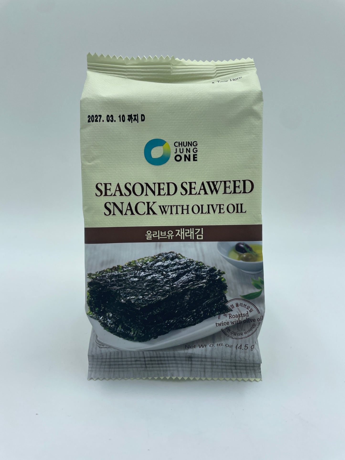 Dækket med krydret tangsnack med olivenolie fra DAESANG, vises i en tydelig pose med sprøde, krydrede tangflager.